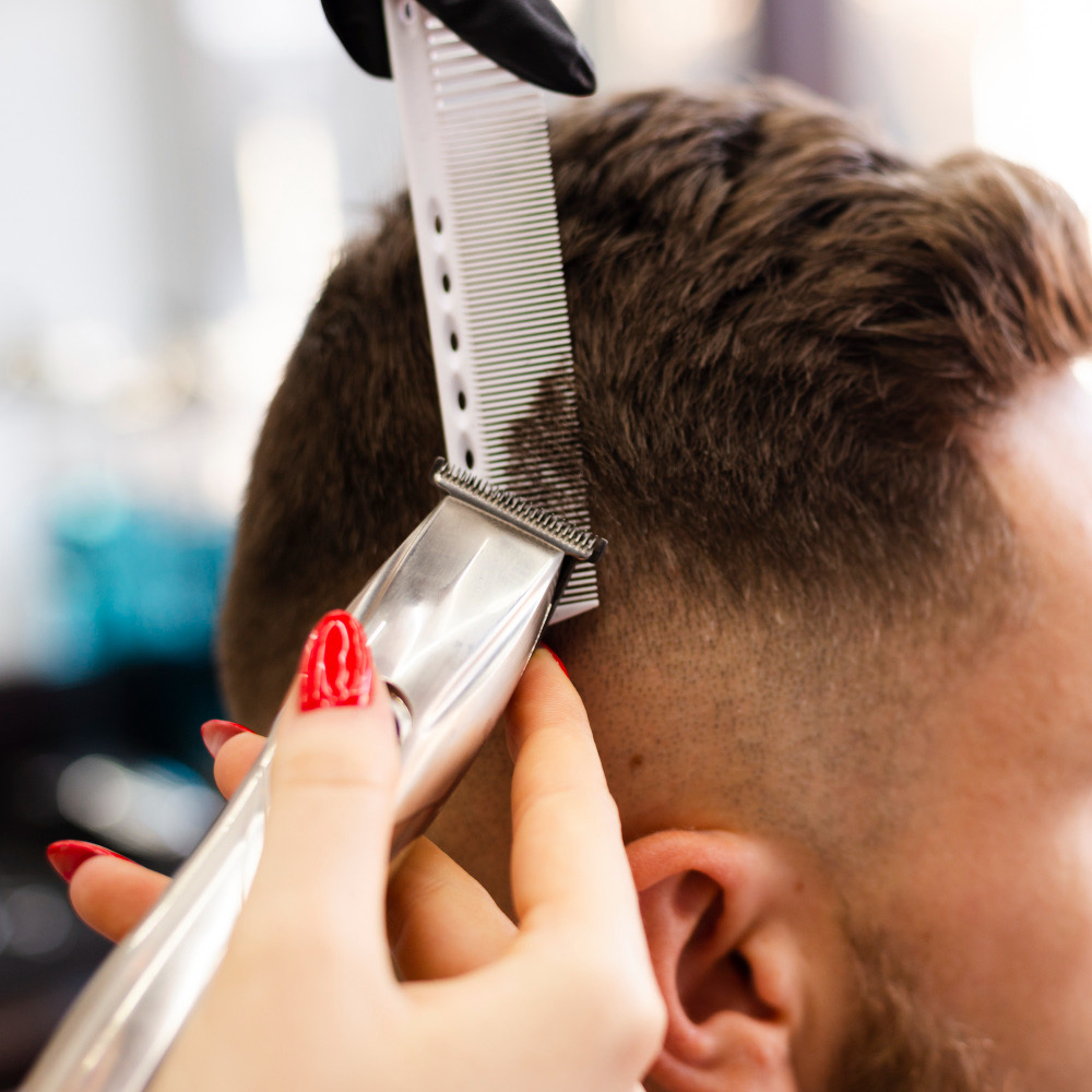 Close-up of a precision men's haircut in progress at Refined Gents — clippers and comb blending a clean fade